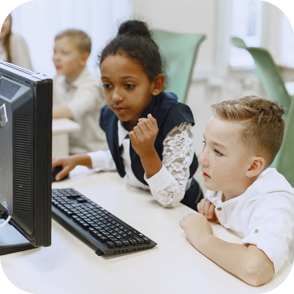 Image of two young students using a computer at school.
